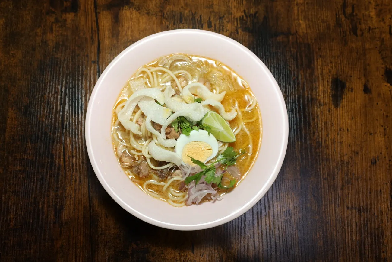 A bowl of coconut noodle soup with chicken